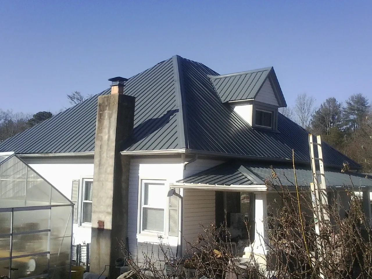 Dark blue standing seam metal roof on a white farmhouse with dormer — Slate & Tile Roof Repair by Roofing Brothers in Castro Valley