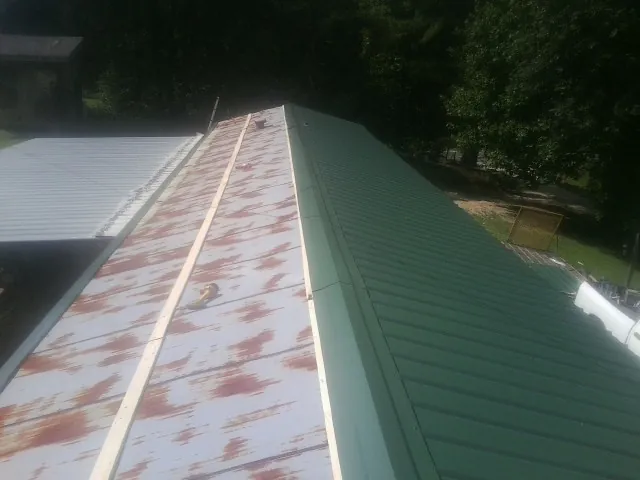 Old rusted panels beside newly installed green metal roofing — Wind Damage Roof Repair by Roofing Brothers in Castro Valley