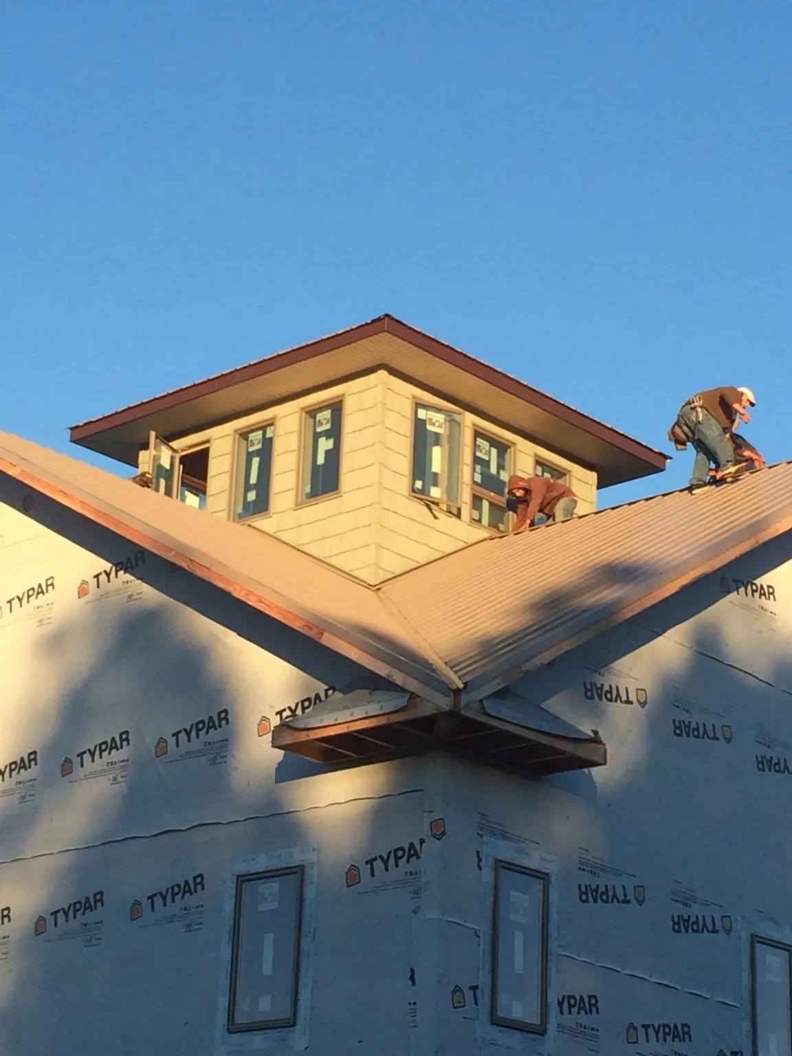 Roofers working around a rooftop cupola on a new metal roof at sunset — Roof Waterproofing in Castro Valley by Roofing Brothers